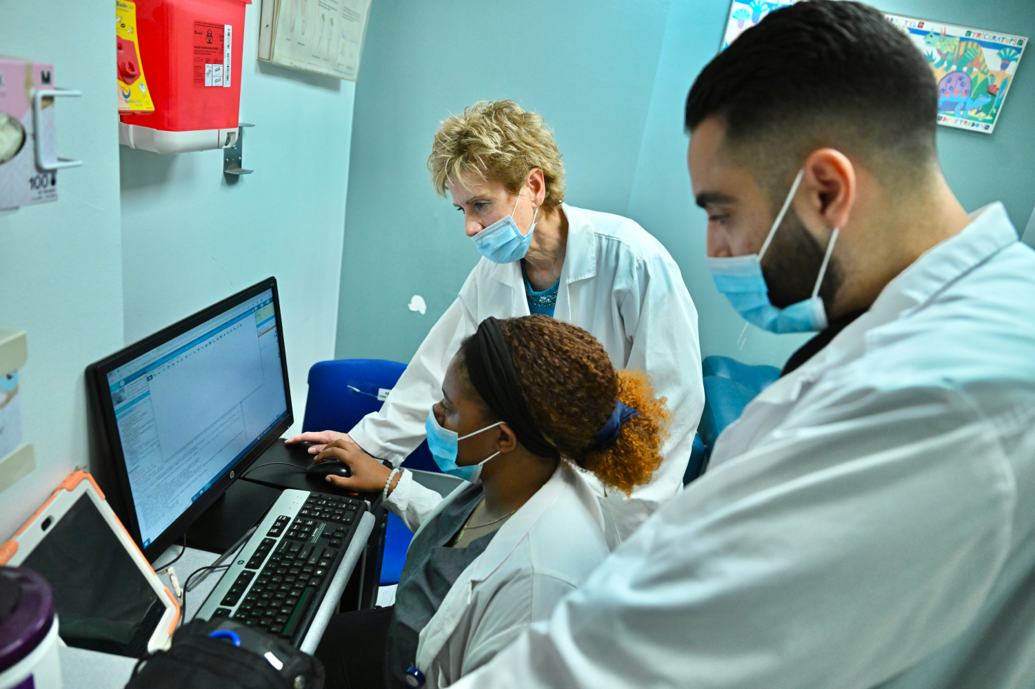 Students and instructor looking at computer in examining room