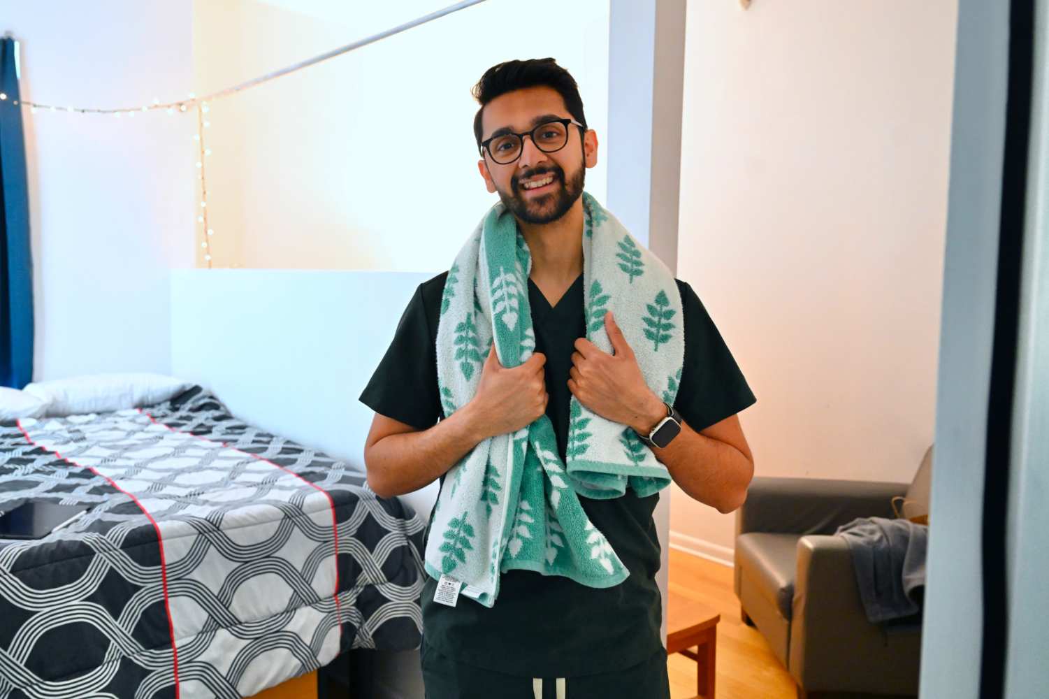 Student smiling while standing next to bed in room at The Bridges